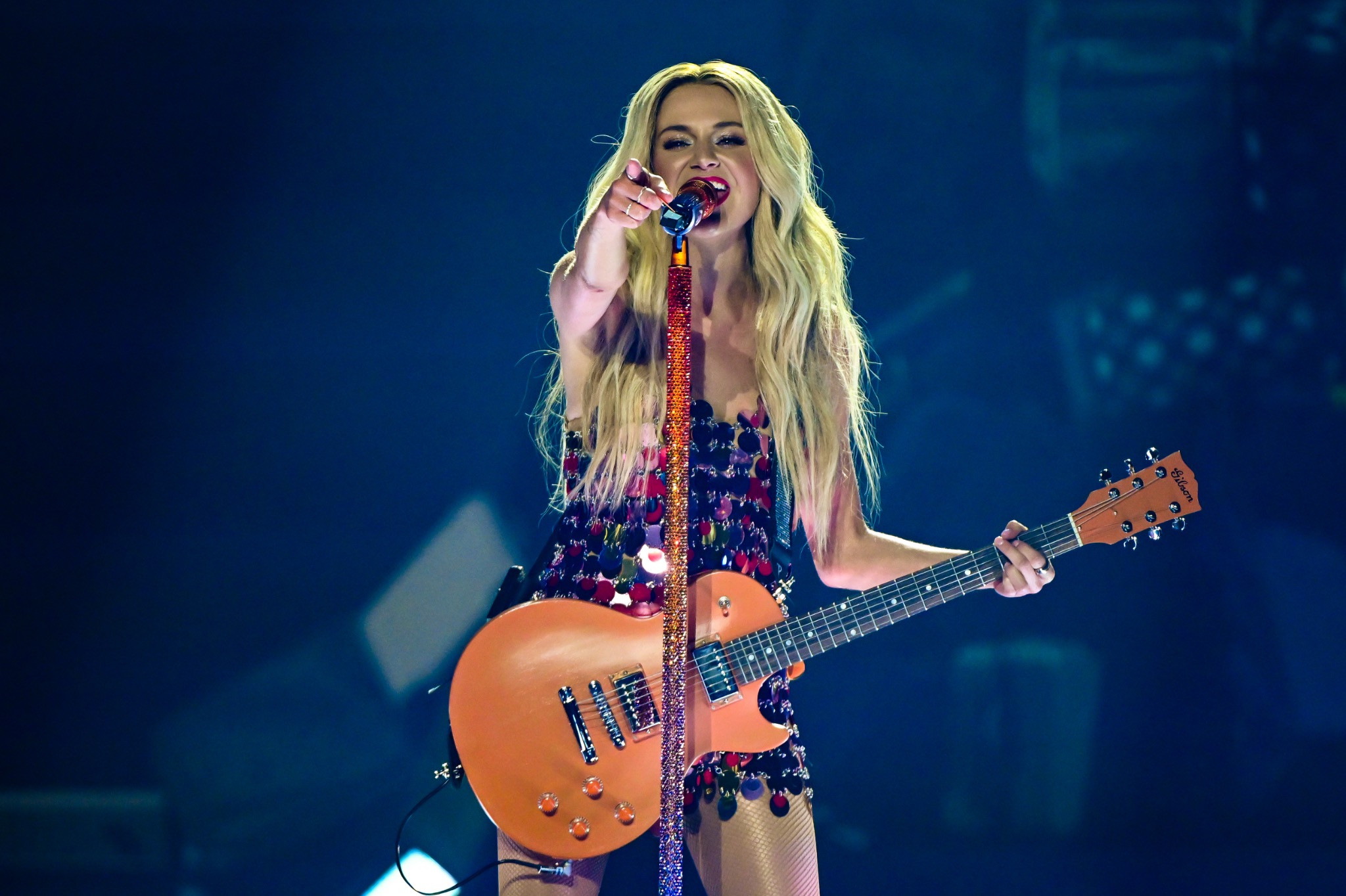 Artist playing guitar under concert lighting