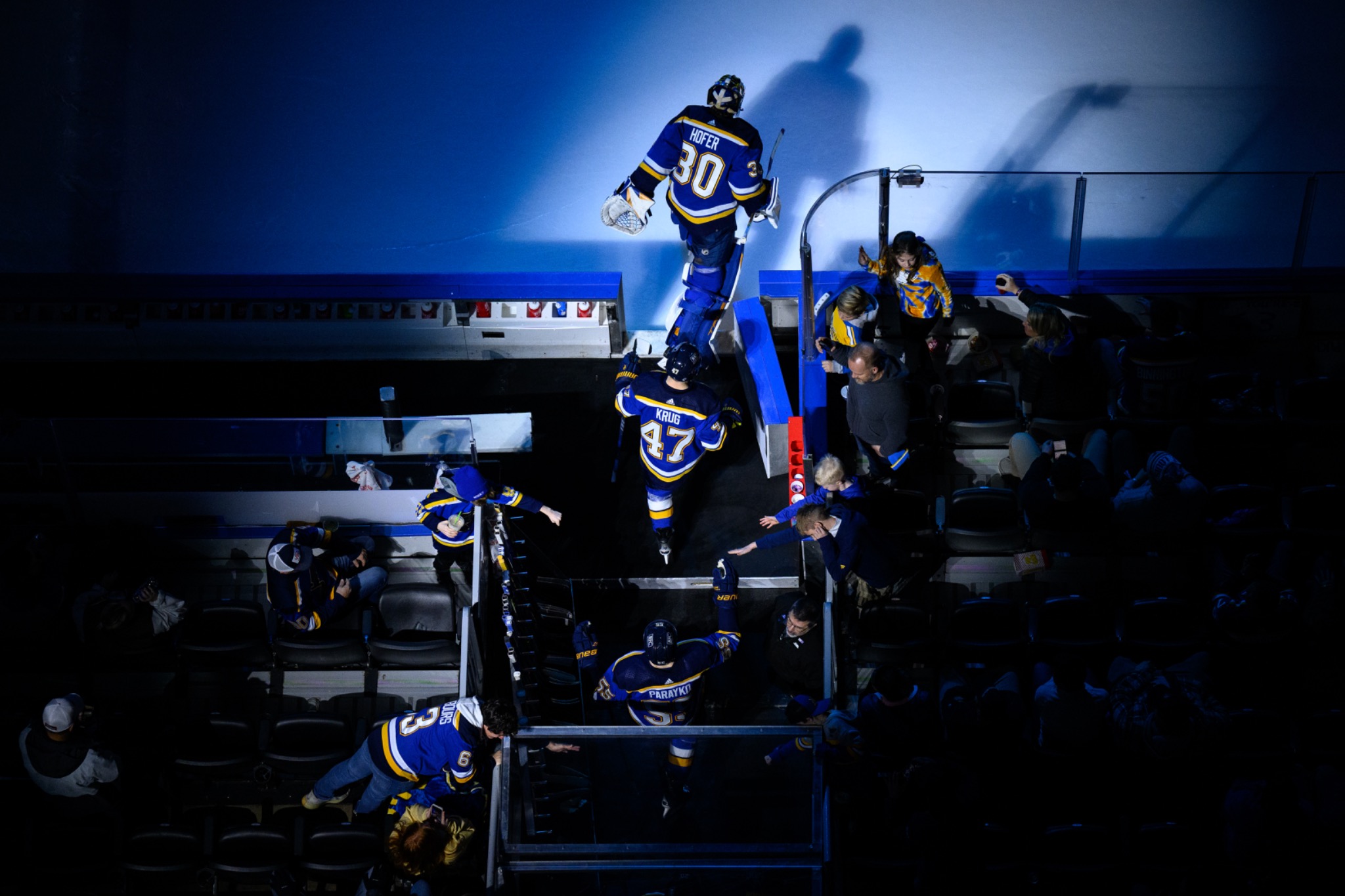 St. Louis Blues players moving through a dramatic arena tunnel