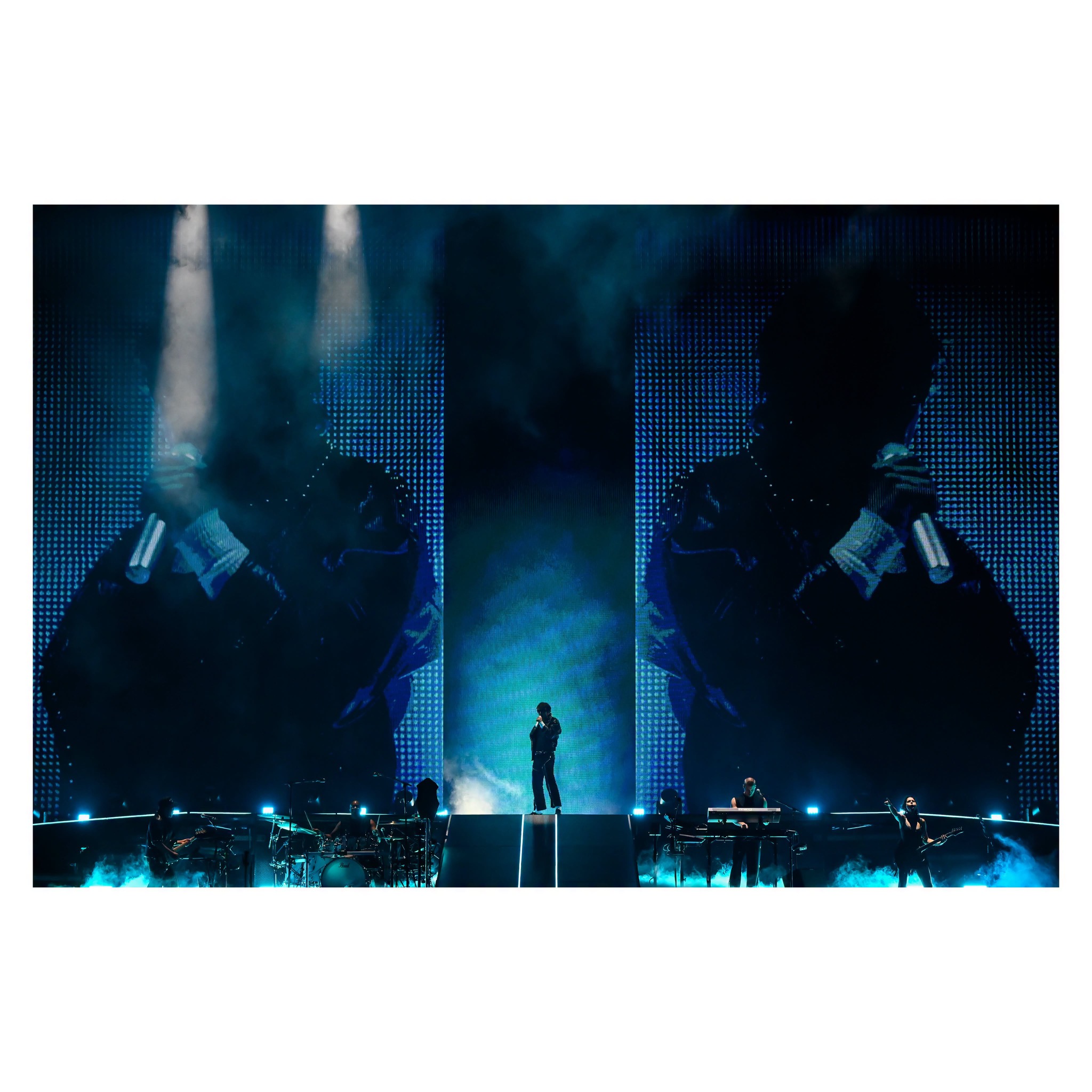 Performer silhouetted within a wide blue-lit concert production