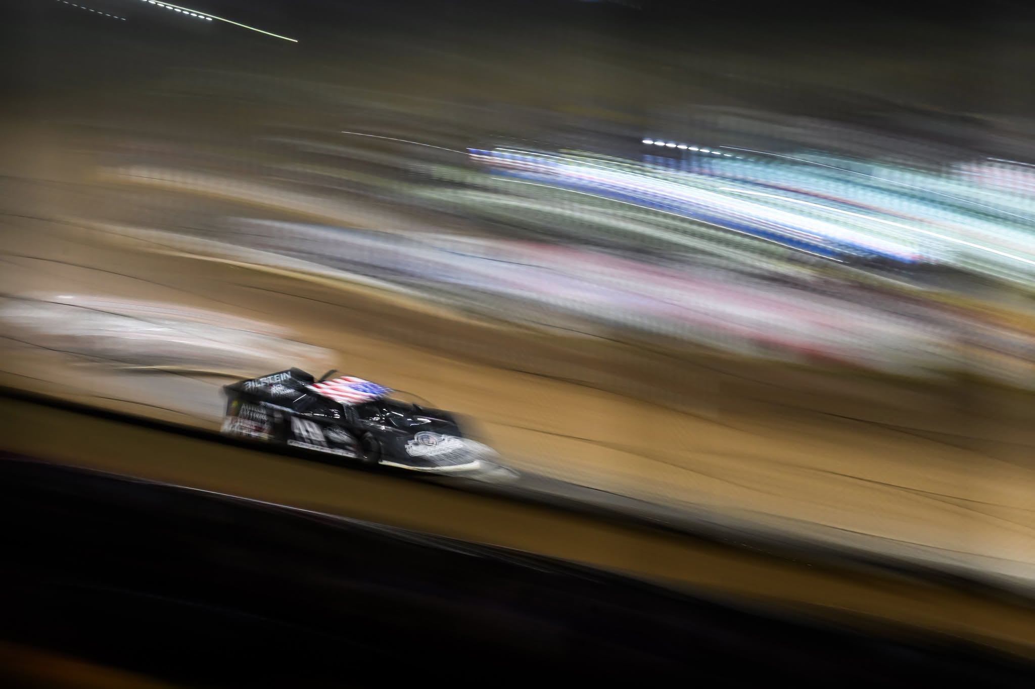 Dirt late model isolated against streaked lights in a panning photograph