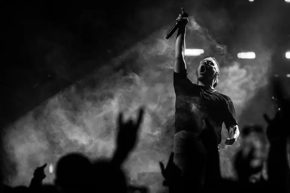 Performer framed with concert crowd and theatrical smoke