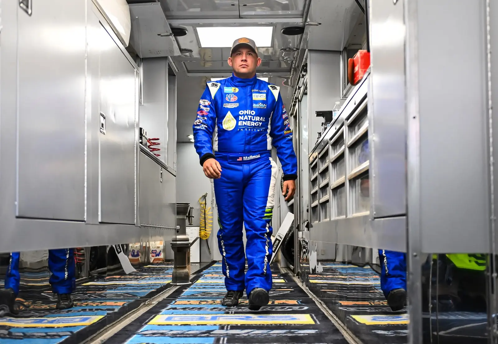 Race driver in a blue suit walking through a team hauler
