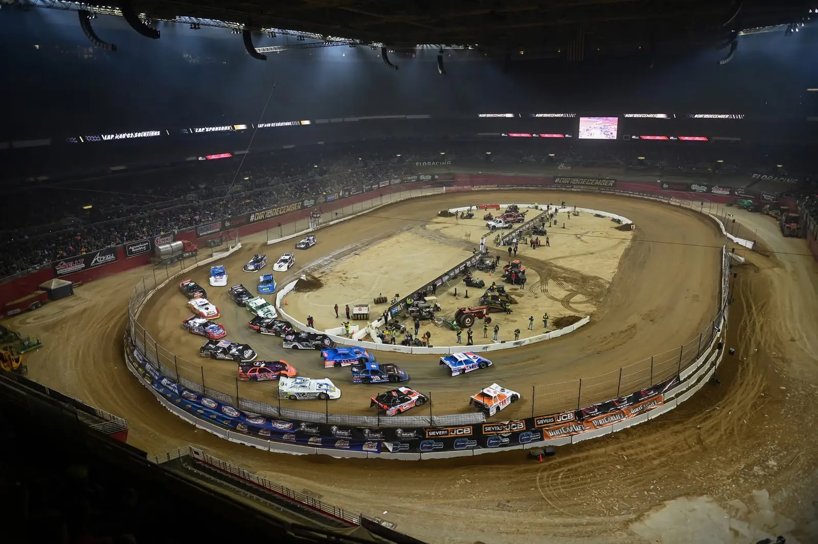 Wide overhead view of dirt racing inside a large indoor arena