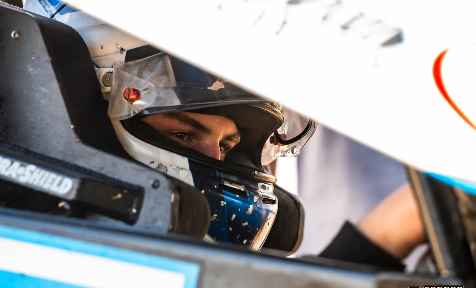 Close-up of a helmeted race driver concentrating inside the cockpit