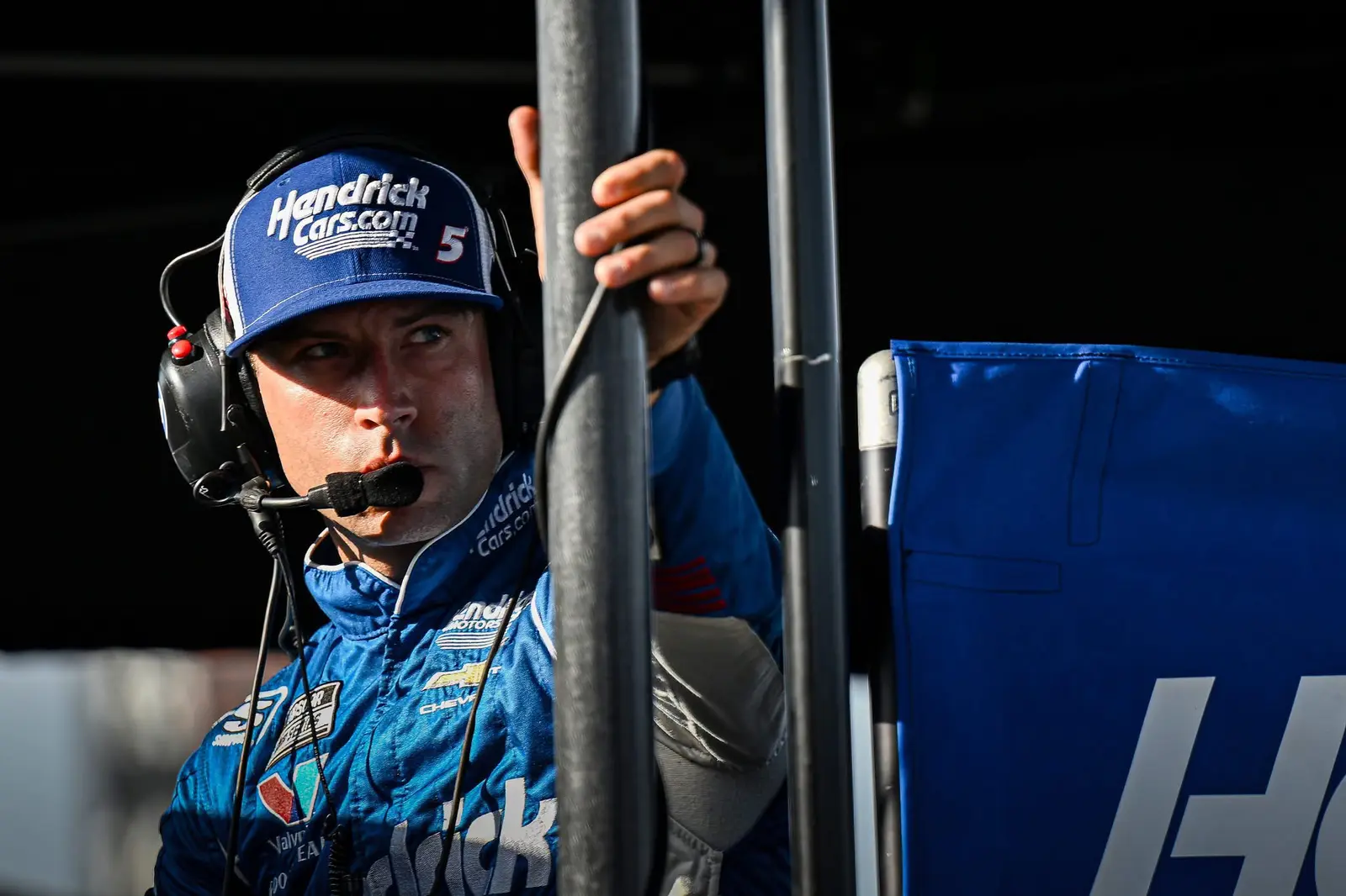Race crew member framed by equipment in directional garage light