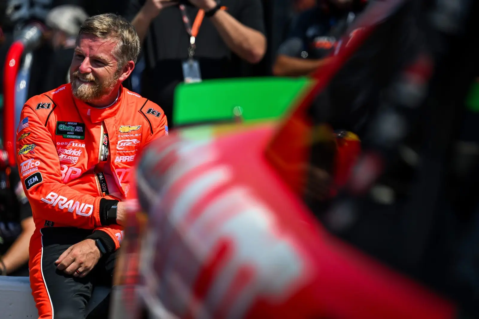 Race driver sharing a candid emotional moment beside pit equipment