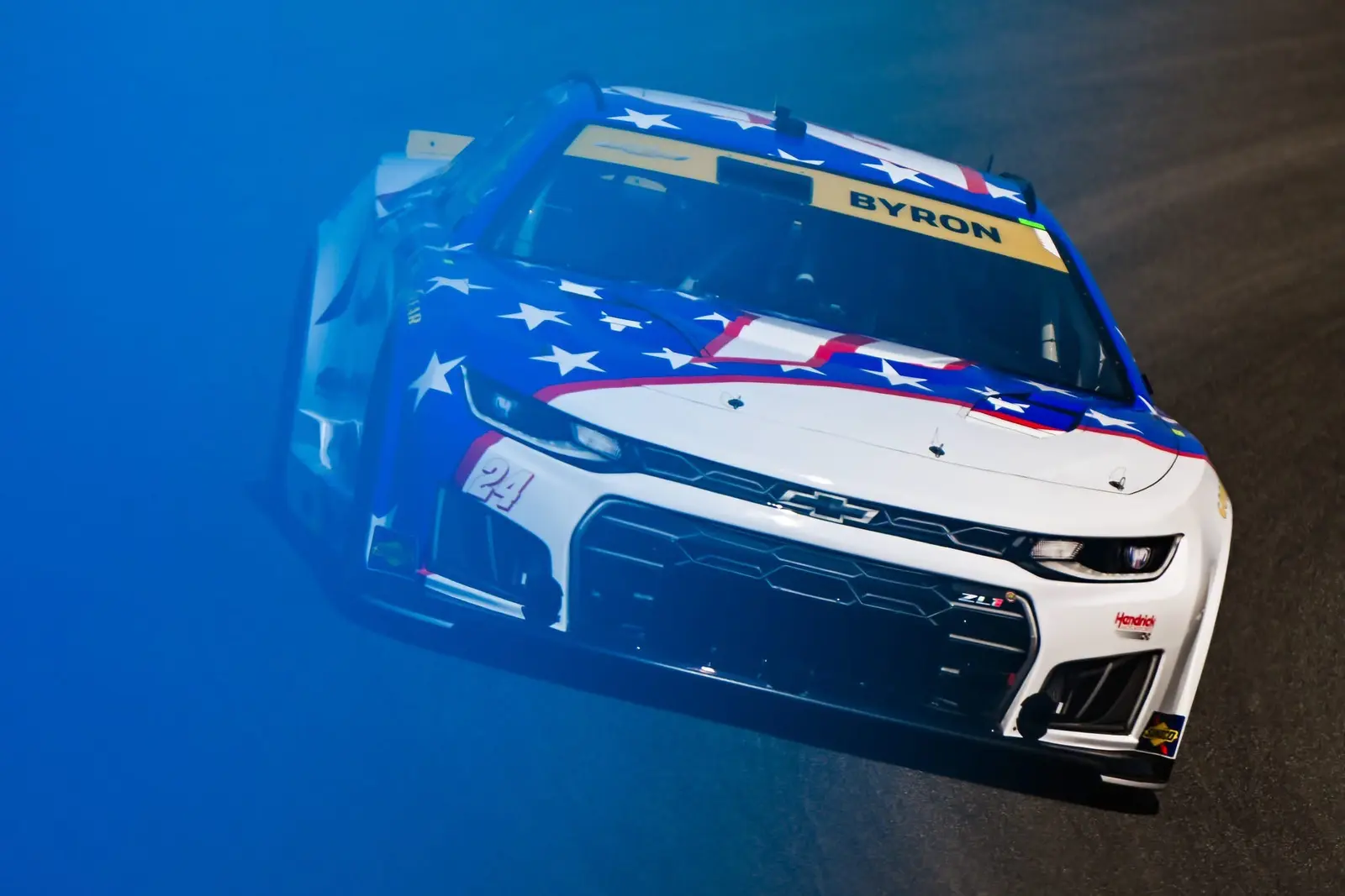 NASCAR race car emerging through layered blue foreground color on track