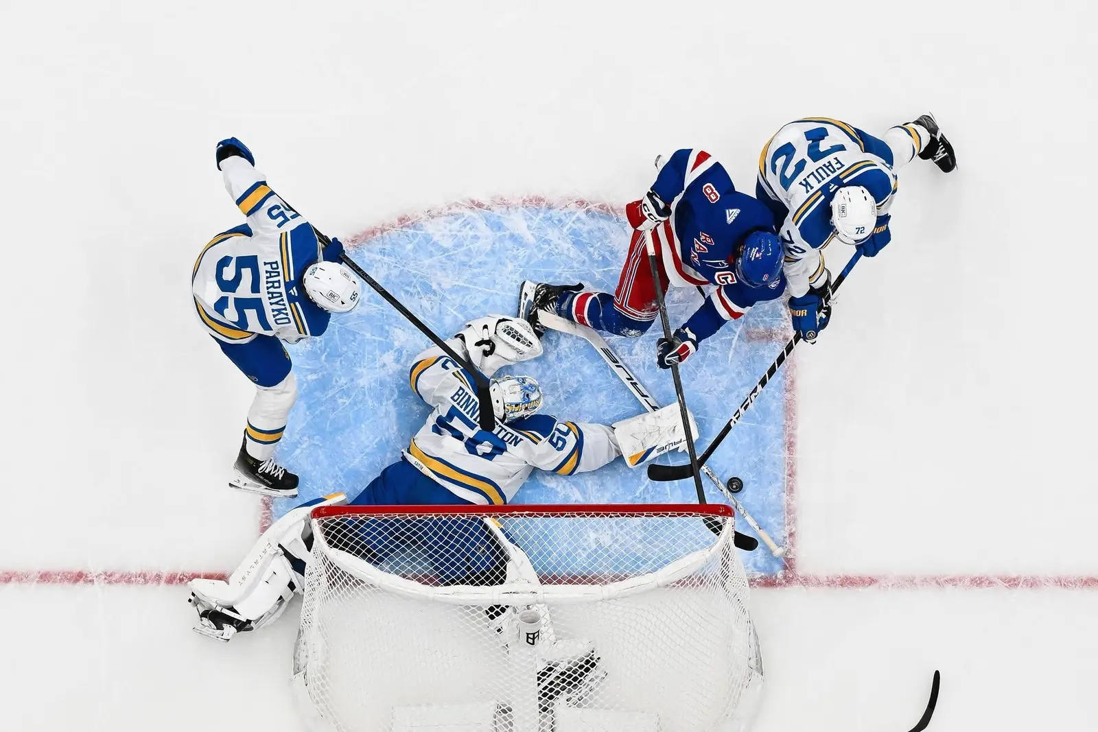 Overhead view of players battling for the puck around a hockey goal crease