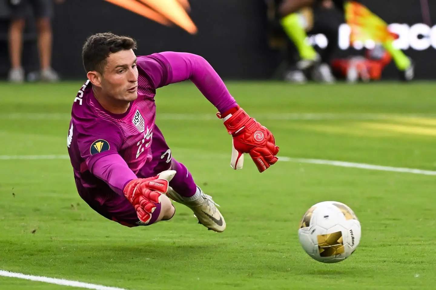 United States goalkeeper diving toward the ball during an international soccer match